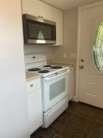 a kitchen with granite countertop white cabinets and stainless steel appliances