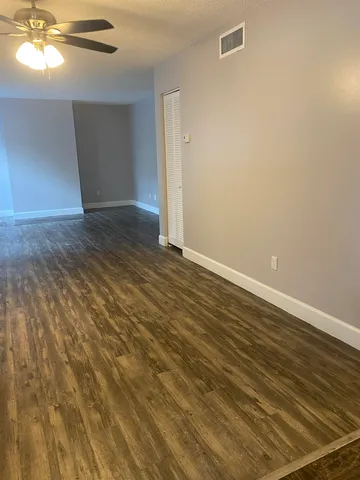 a view of an empty room with window and wooden floor