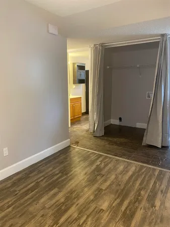 an empty room with wooden floor and a bathroom