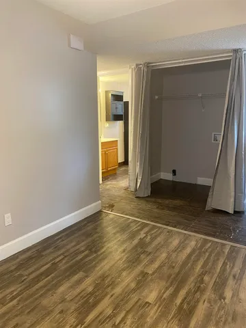 an empty room with wooden floor and a bathroom