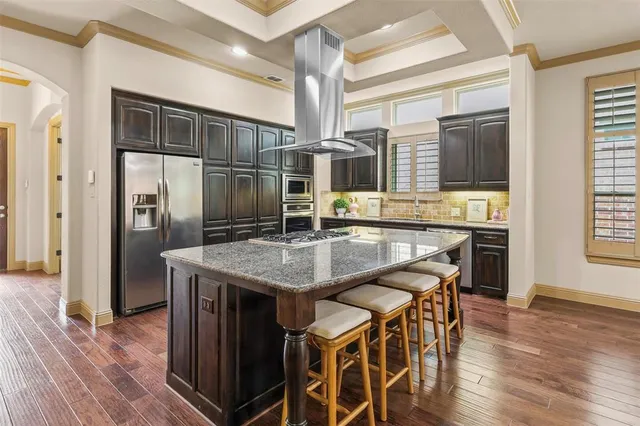 a kitchen with stainless steel appliances kitchen island granite countertop a table chairs and wooden cabinets