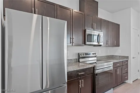 a kitchen with stainless steel appliances granite countertop a sink a stove a refrigerator and cabinets