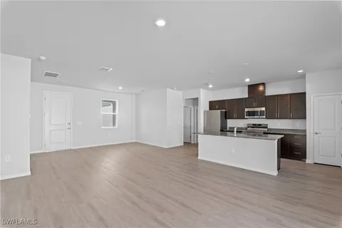 a kitchen with granite countertop a table chairs and wooden floor