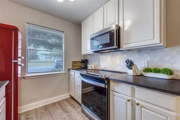 a kitchen with stainless steel appliances granite countertop white cabinets and a stove top oven