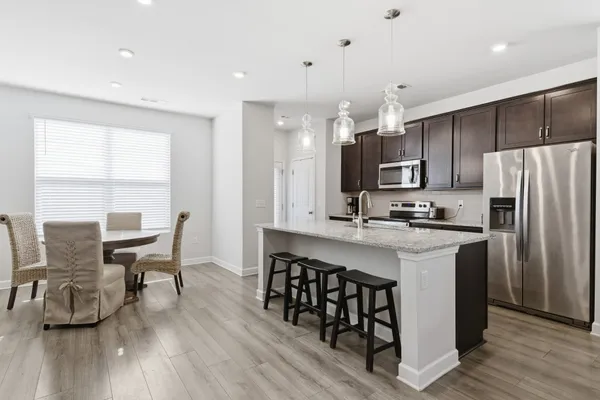 a kitchen with stainless steel appliances a dining table chairs microwave and sink