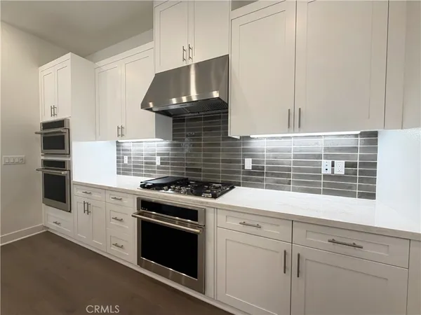 a kitchen with stainless steel appliances white cabinets and a stove top oven