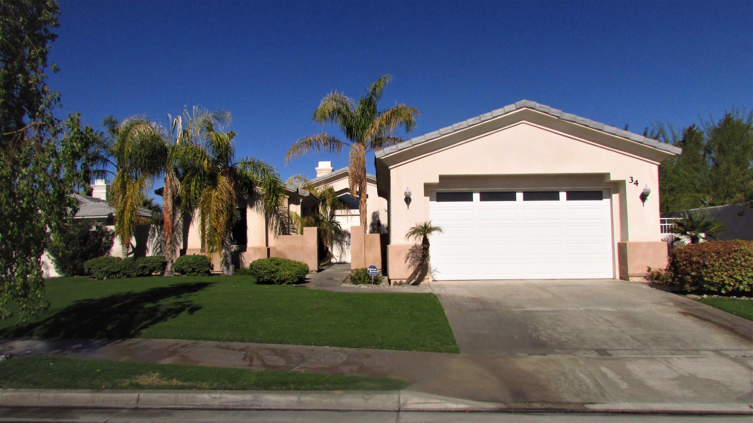 34 Paris Way Rancho Mirage, CA 92270 - Photo 2 of 35 a front view of a house with a yard and garage