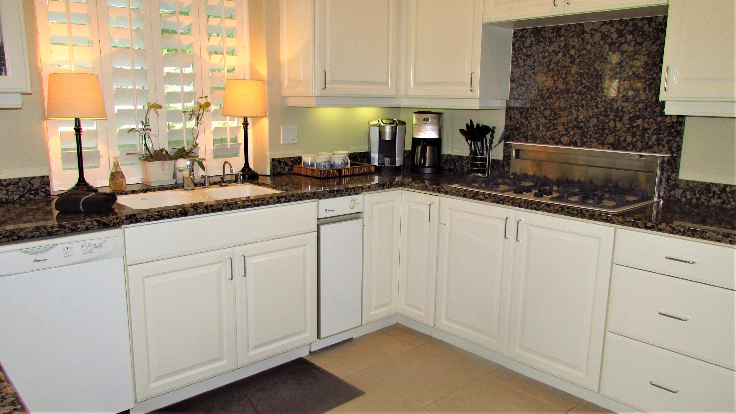 34 Paris Way Rancho Mirage, CA 92270 - Photo 9 of 35 a kitchen with granite countertop white cabinets and white appliances