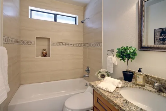 a bathroom with a granite countertop sink a toilet and tub