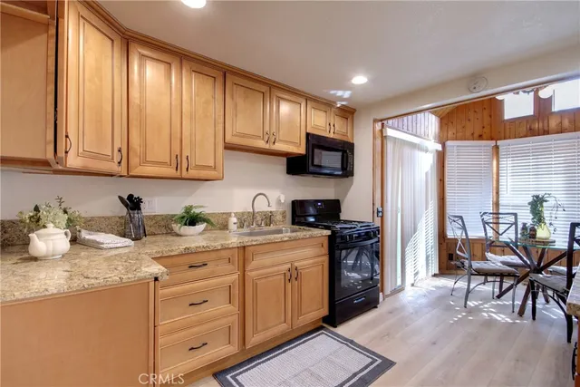 a kitchen with stainless steel appliances granite countertop a stove top oven a sink dishwasher and a refrigerator with wooden cabinets