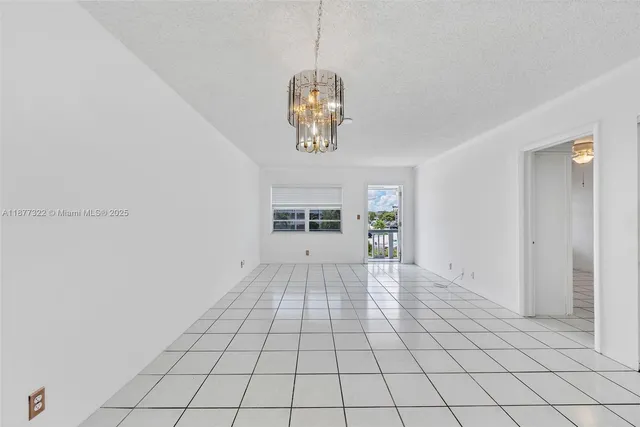 a view of an empty room with window and chandelier fan