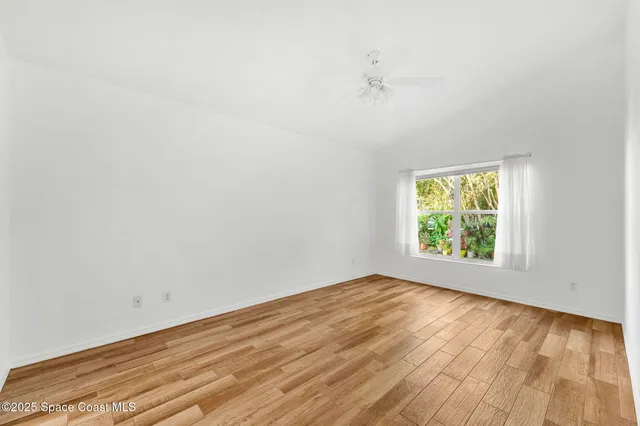 an empty room with a window and a ceiling fan
