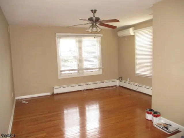 a view of an empty room with a window and wooden floor