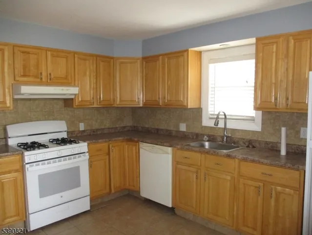 a kitchen with granite countertop cabinets stainless steel appliances a sink and window