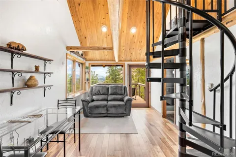 a living room with furniture large window and wooden floor