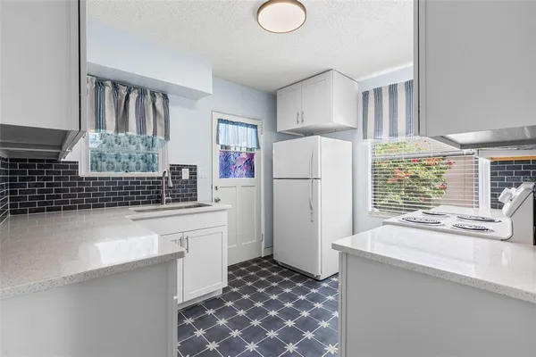 a kitchen with a sink a stove and white cabinets