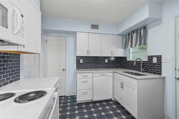 a kitchen with granite countertop white cabinets and white appliances