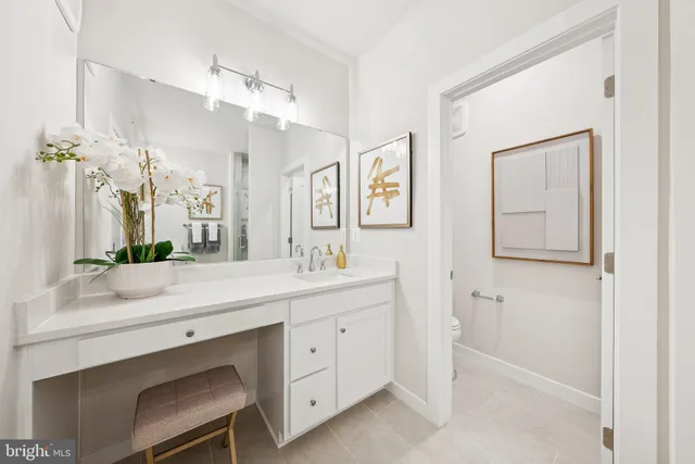 a bathroom with a granite countertop sink mirror vanity bathtub and toilet