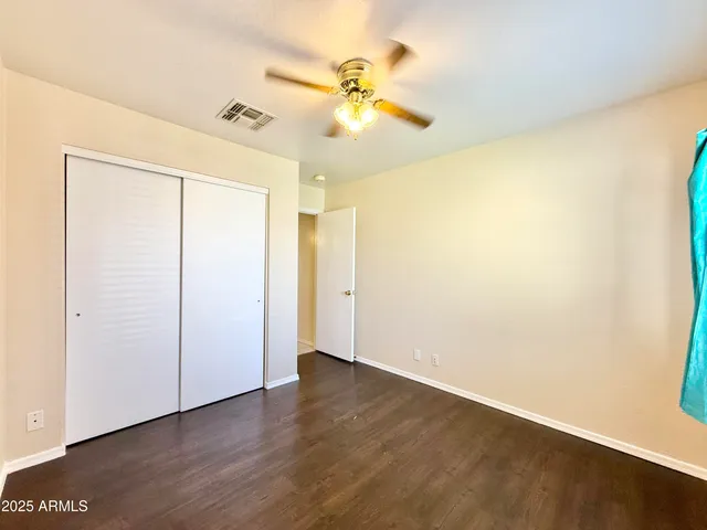 an empty room with wooden floor fan and windows