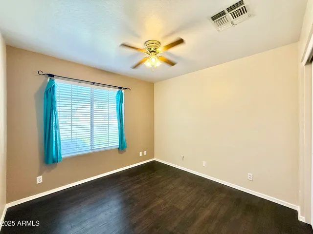 a view of an empty room with window and wooden floor