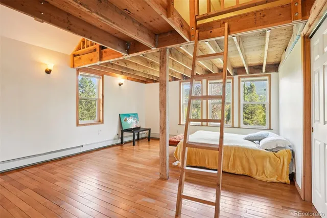 a living room with a bed and wooden floor