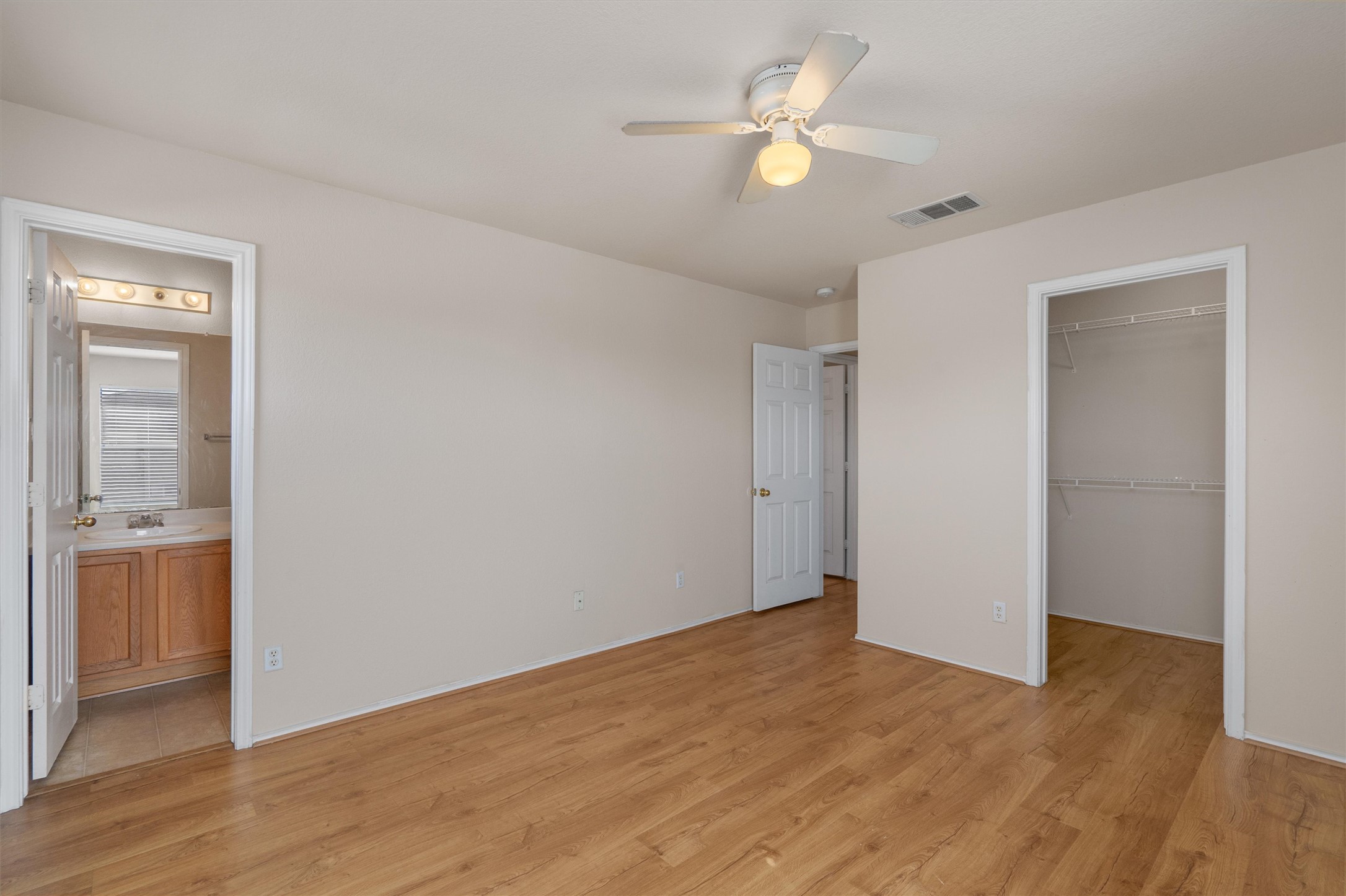 13720 Harris Ridge Boulevard, Unit A Pflugerville, TX 78660 - Photo 14 of 27 Unfurnished bedroom with a walk in closet, light wood-style flooring, ceiling fan, and ensuite bath