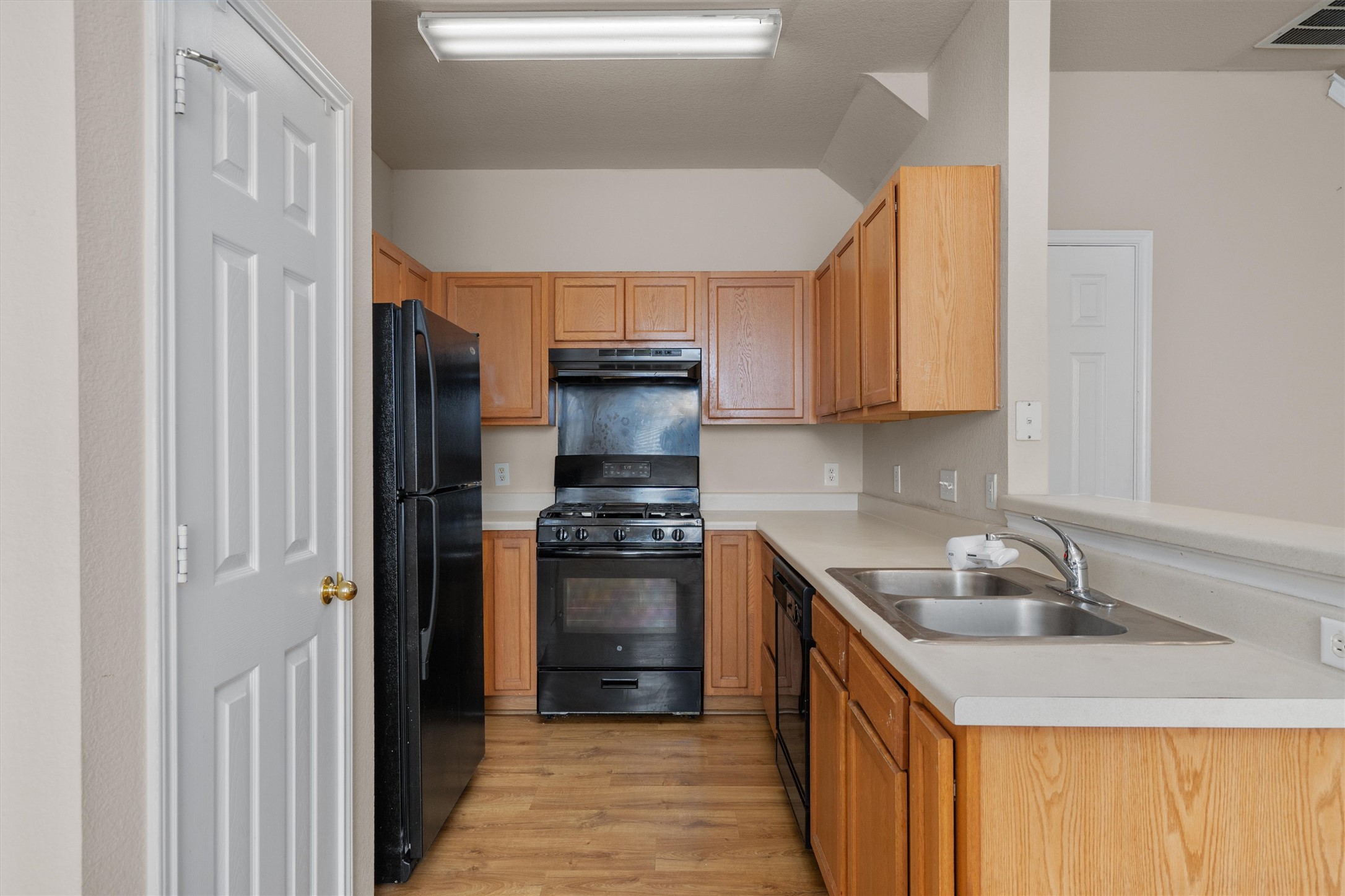 13720 Harris Ridge Boulevard, Unit A Pflugerville, TX 78660 - Photo 8 of 27 Kitchen with black appliances, light countertops, light wood-style flooring, and a peninsula
