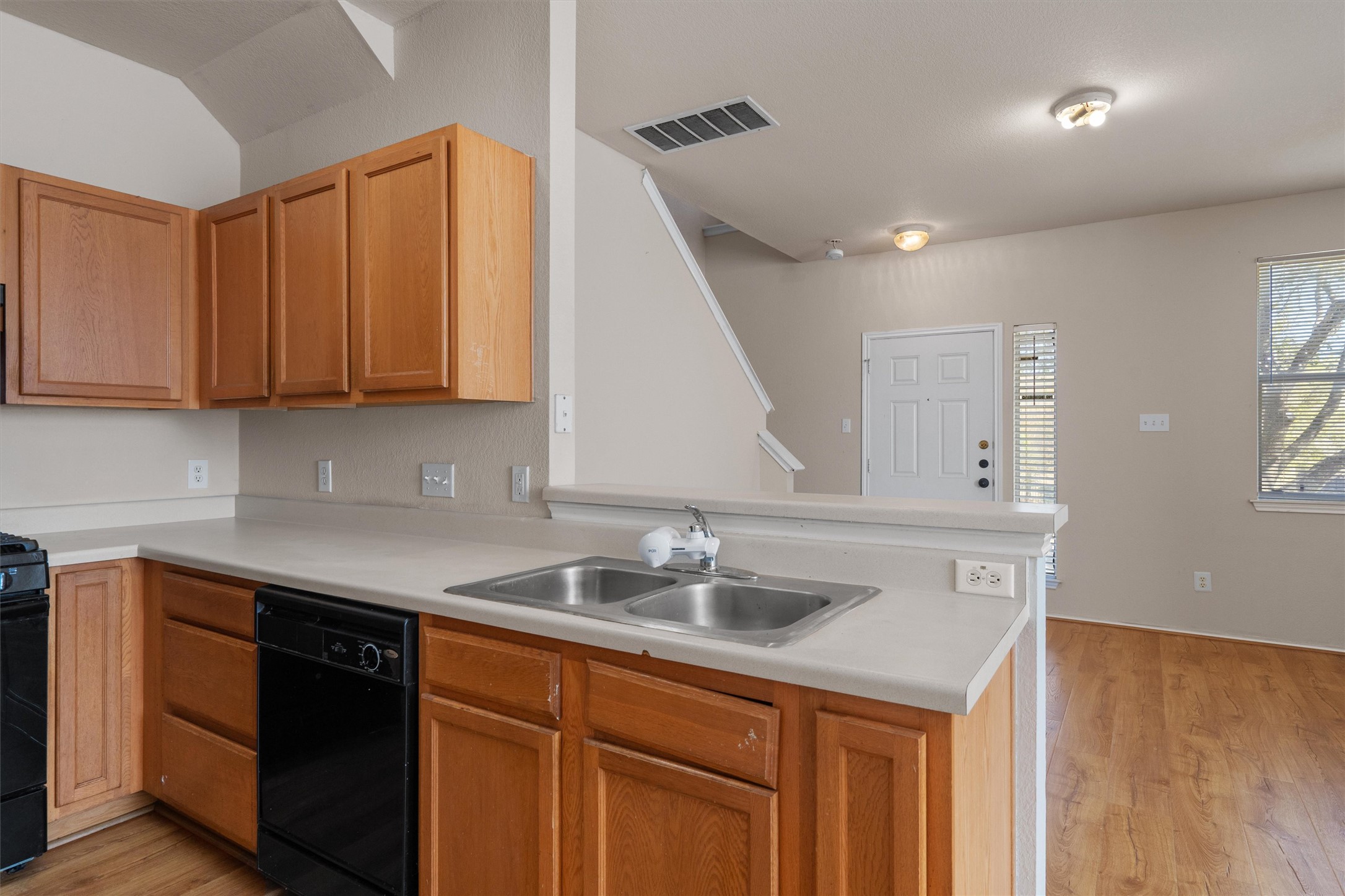 13720 Harris Ridge Boulevard, Unit A Pflugerville, TX 78660 - Photo 9 of 27 Kitchen with light countertops, black appliances, a peninsula, and light wood-type flooring