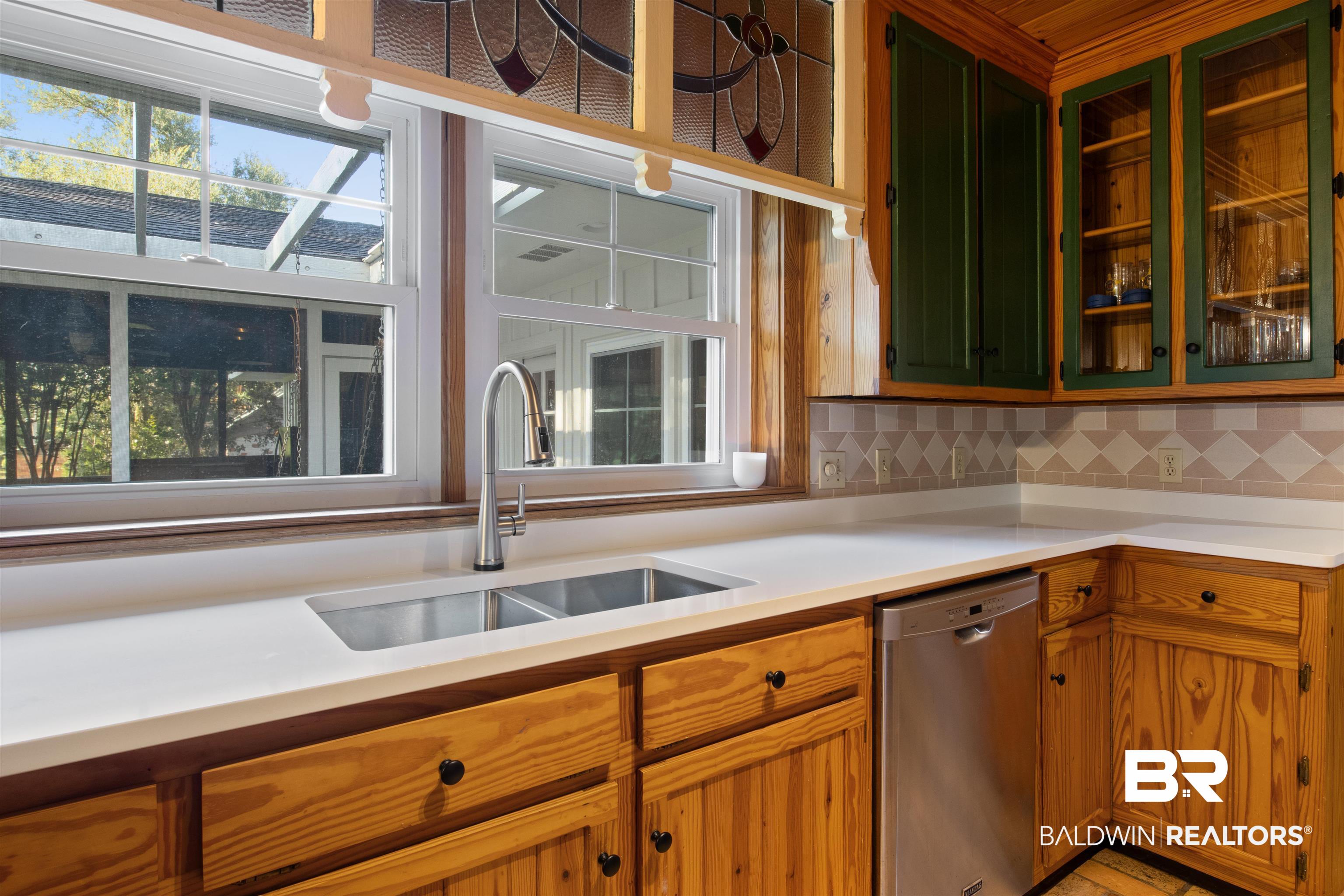 15100 Vasko Road Silverhill, AL 36576 - Photo 10 of 51 Kitchen featuring backsplash, sink, and stainless steel dishwasher. Custom cabinetry provides solid wood doors as well as glassed doors.