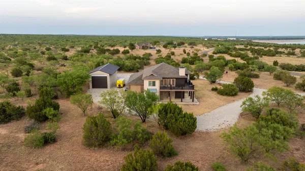 an aerial view of residential houses with outdoor space and trees