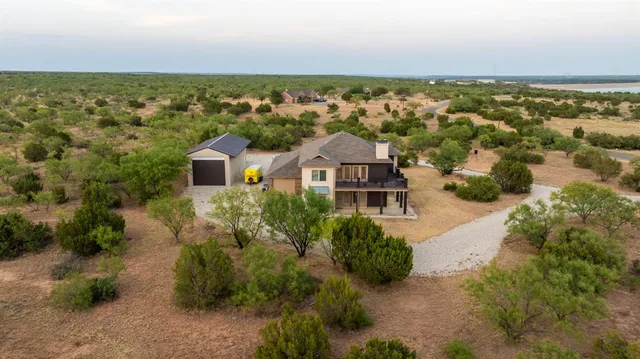 an aerial view of residential houses with outdoor space and trees