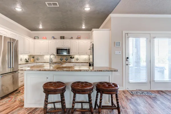 a kitchen with stainless steel appliances granite countertop a table chairs sink and cabinets