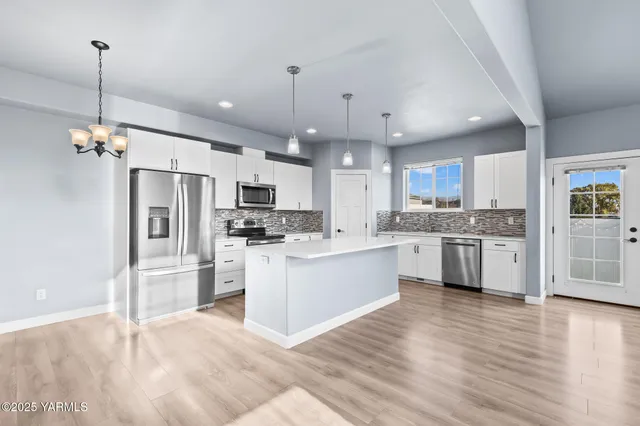 a large kitchen with white cabinets stainless steel appliances and a center island