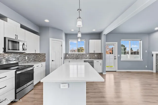 a large kitchen with granite countertop a stove top oven a sink dishwasher a dining table and chairs with wooden floor