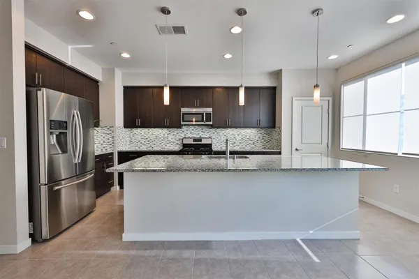 a large kitchen with granite countertop a large counter top stainless steel appliances and cabinets