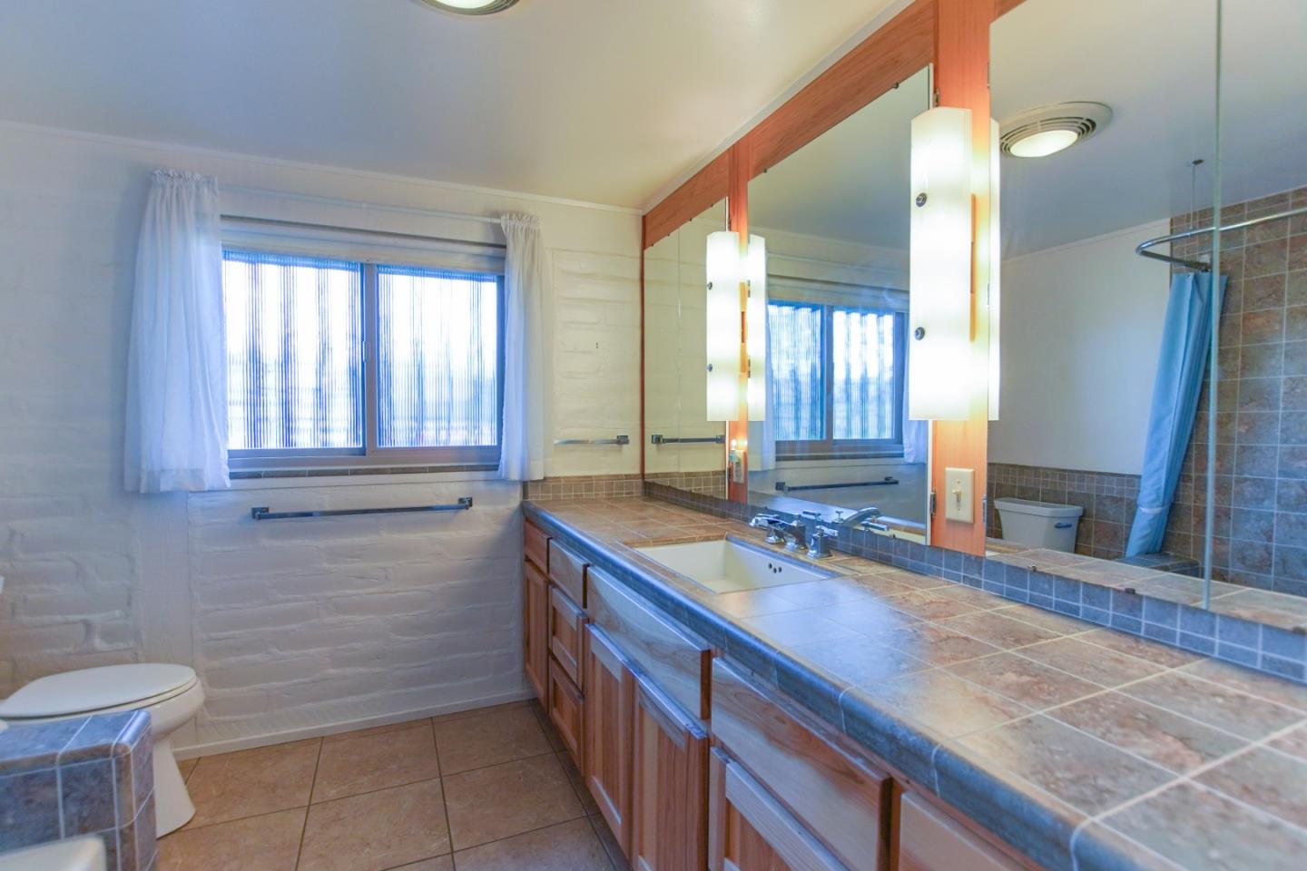 1521 Cienega Road Hollister, CA 95023 - Photo 28 of 56 a bathroom with a granite countertop sink a toilet and mirror