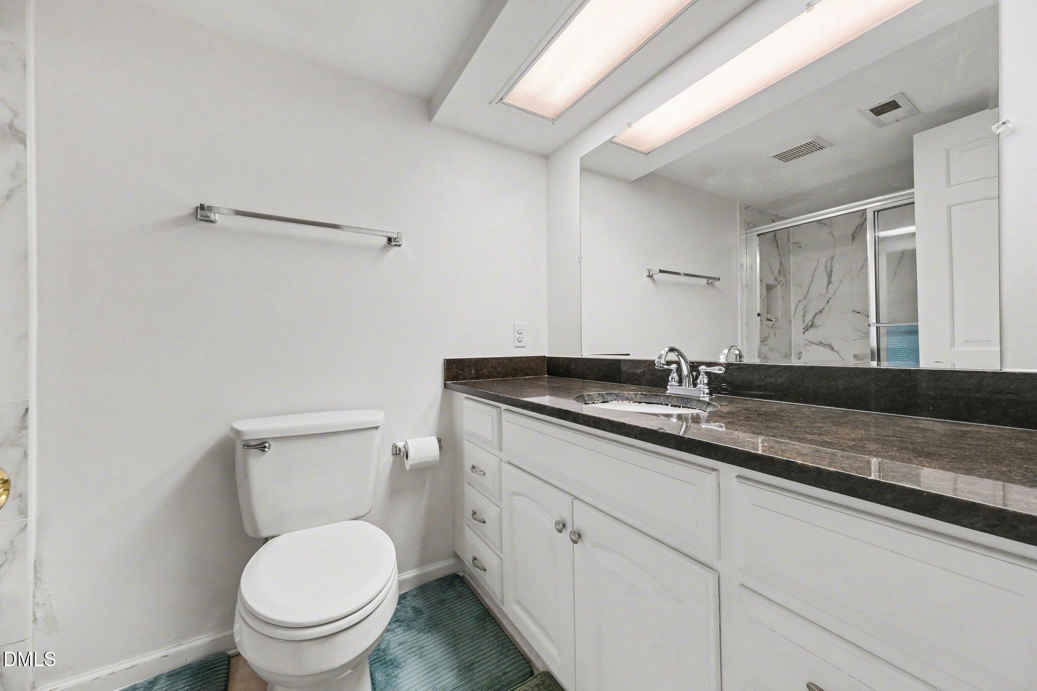 1911 Front Street, Unit 3B Durham, NC 27705 - Photo 24 of 33 a bathroom with a granite countertop toilet sink and mirror