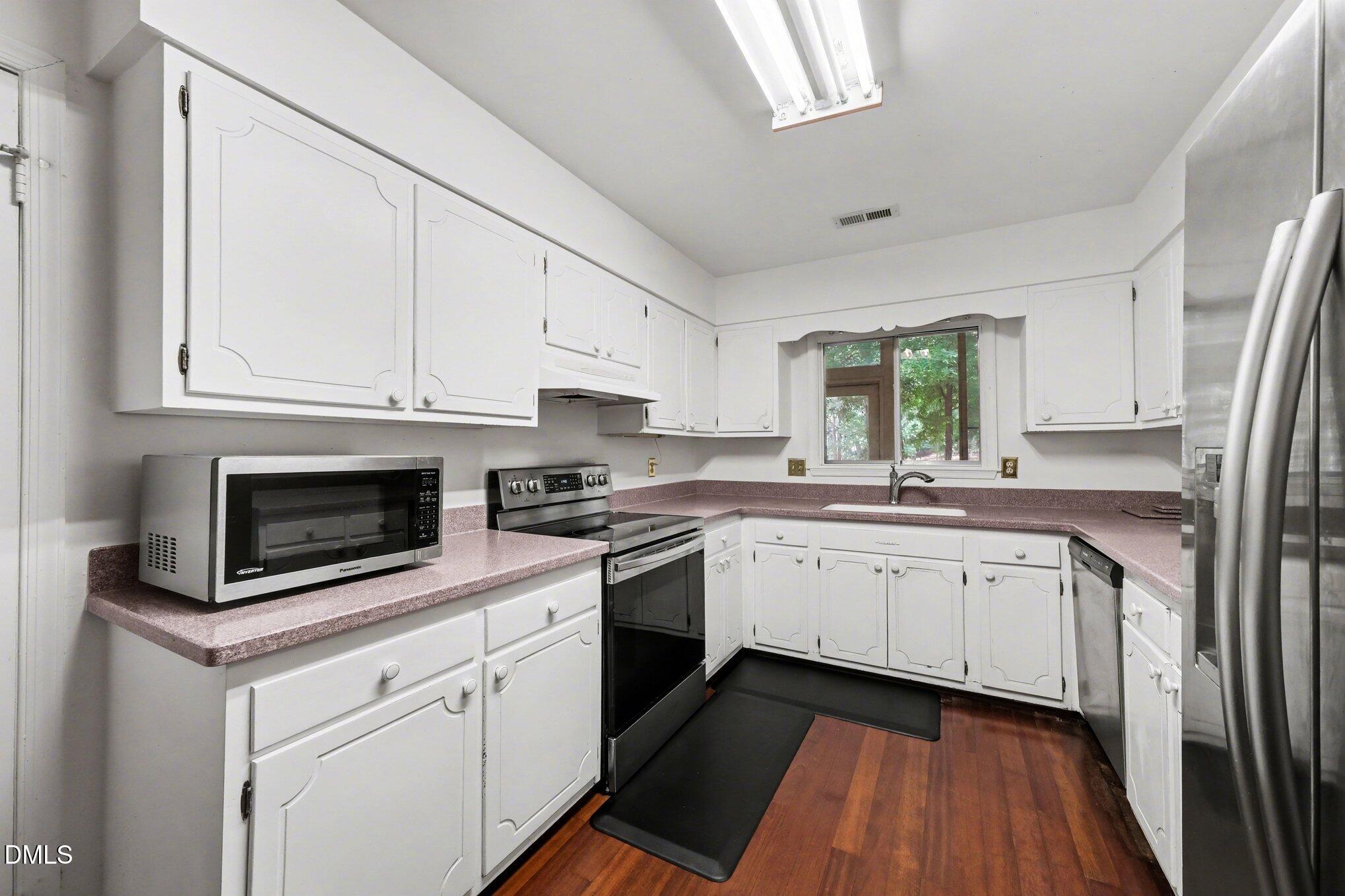 1911 Front Street, Unit 3B Durham, NC 27705 - Photo 9 of 33 a kitchen with granite countertop white cabinets stainless steel appliances a sink and a window