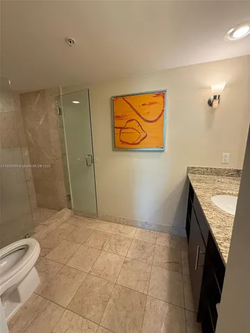 a bathroom with a granite countertop sink a toilet and shower