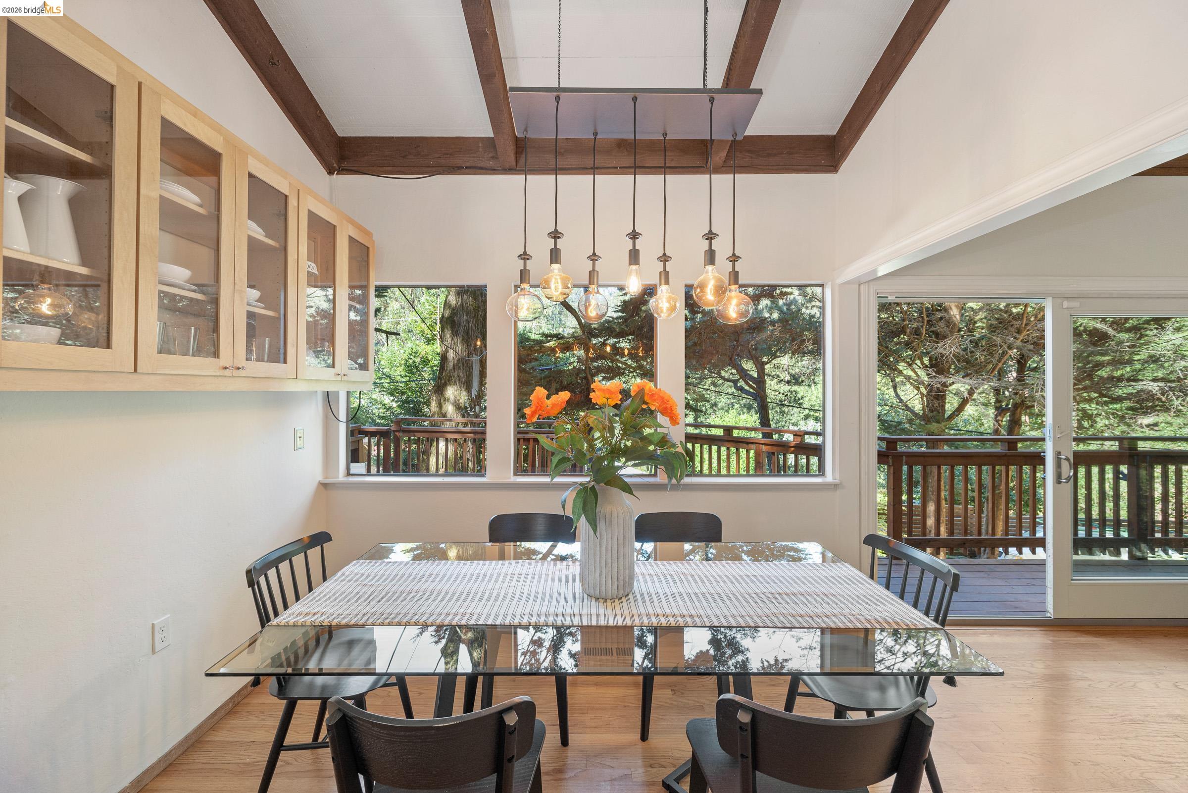 6600 Heather Ridge Way Oakland, CA 94611 - Photo 17 of 66 Vaulted ceiling featuring exposed wood beams, wood-finish flooring, and a sliding glass door leading to an outdoor deck