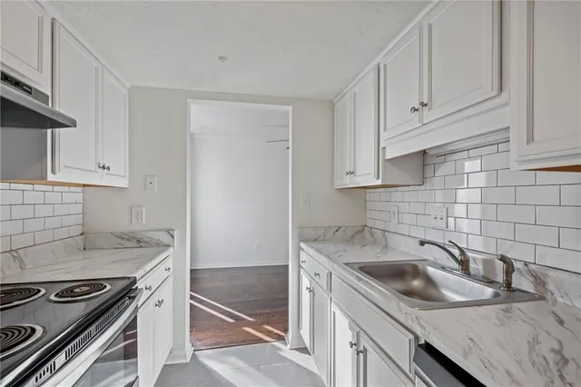 a kitchen with granite countertop a sink stove and cabinets