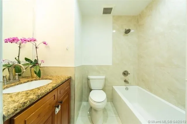 a bathroom with a granite countertop sink a toilet and bathtub