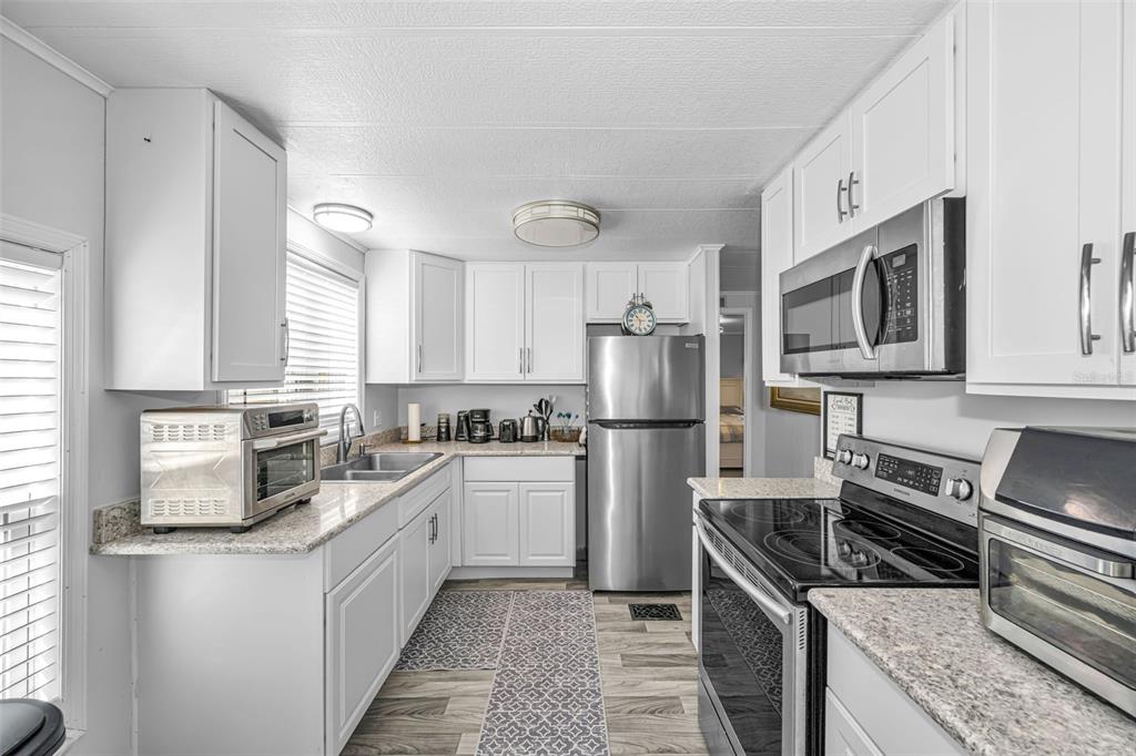 4454 Tucker Square New Port Richey, FL 34652 - Photo 21 of 64 a kitchen with white cabinets and stainless steel appliances