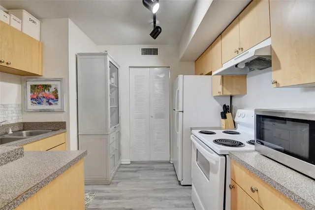 a kitchen with stainless steel appliances granite countertop a refrigerator a stove and a wooden floor