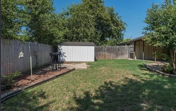 a view of backyard with potted plants and large tree