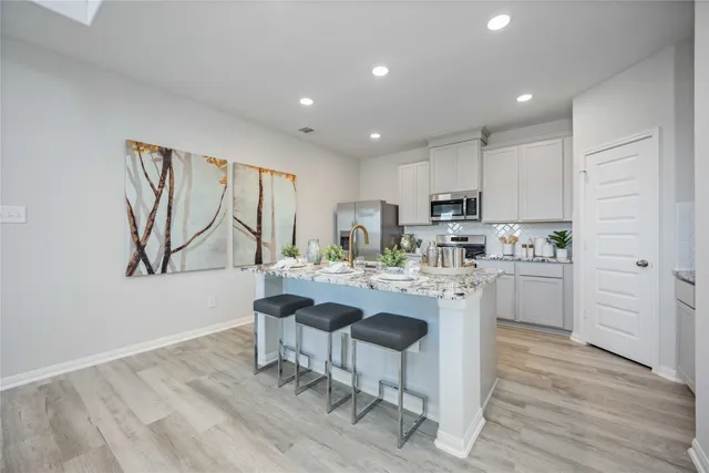 a kitchen with stainless steel appliances granite countertop a stove top oven a sink dishwasher a refrigerator and a microwave oven with wooden floor