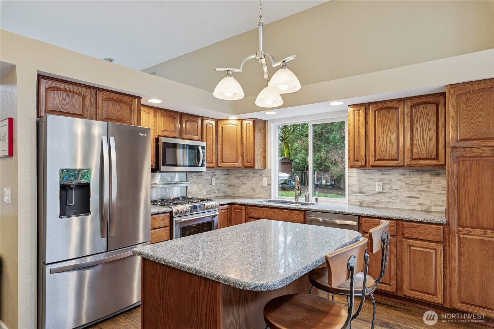 2830 196th Street Southeast Bothell, WA 98012 - Photo 7 of 18 a kitchen with stainless steel appliances granite countertop a refrigerator a sink dishwasher a dining table and chairs with wooden floor