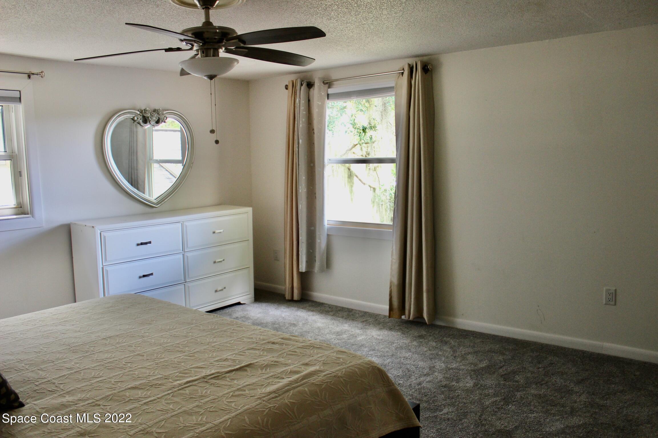 3665 Burkholm Road Mims, FL 32754 - Photo 32 of 62 a bedroom with a bed a mirror on the dresser and a window