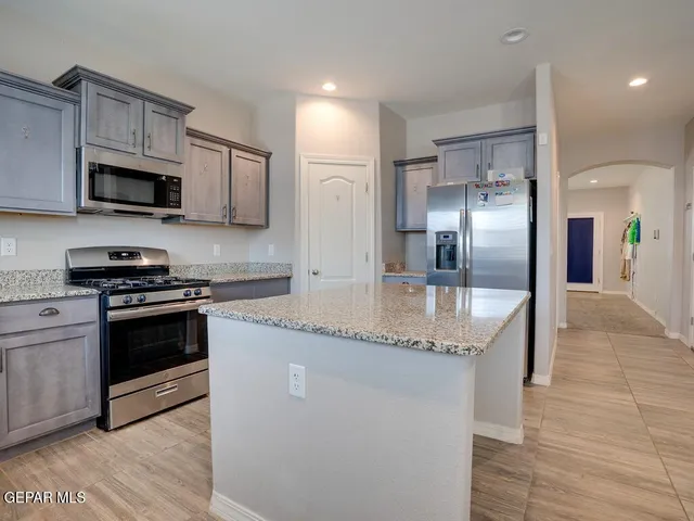 a kitchen with stainless steel appliances granite countertop a sink a stove and a refrigerator