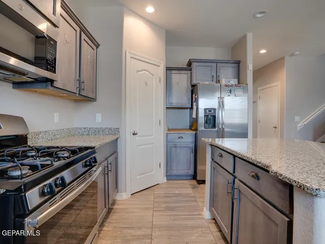 a kitchen with stainless steel appliances granite countertop a stove a refrigerator and a sink